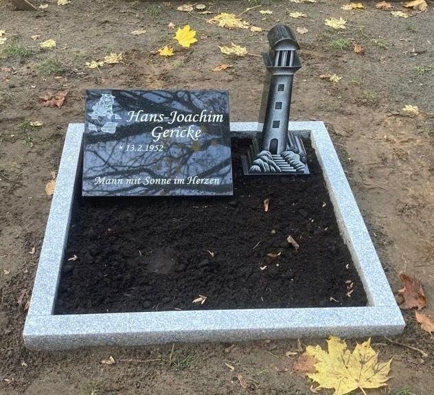Grabstein mit den Namen Hans-Joachim Gericke, einem Datum und einer Leuchtturmskulptur, umgeben von trockenem Erdreich.