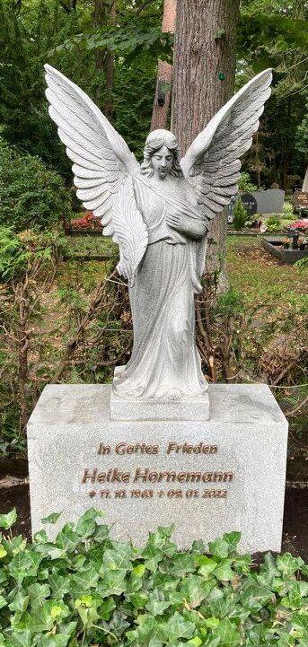 Granitgrabstein mit Engelsskulptur und Inschrift f&uuml;r Helke Hornemann in einem ruhigen, gr&uuml;nen Friedhofsbereich.